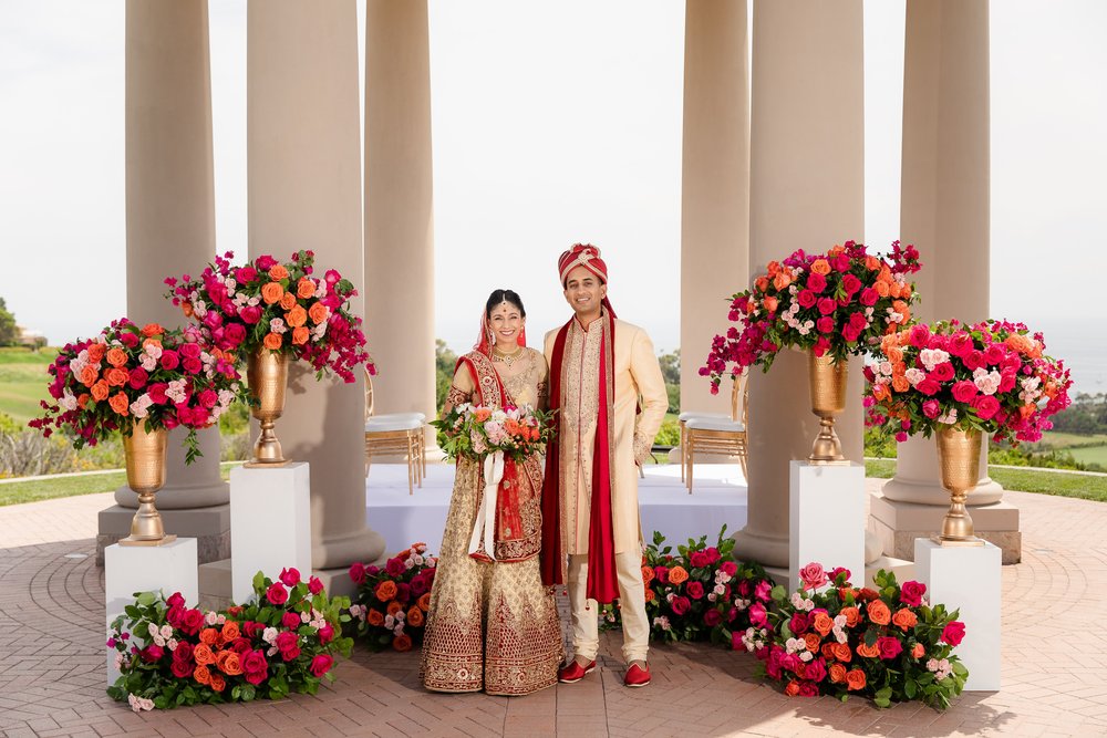 South Asian Bride and Groom pictured with vibrant colored florals at Pelican Hill